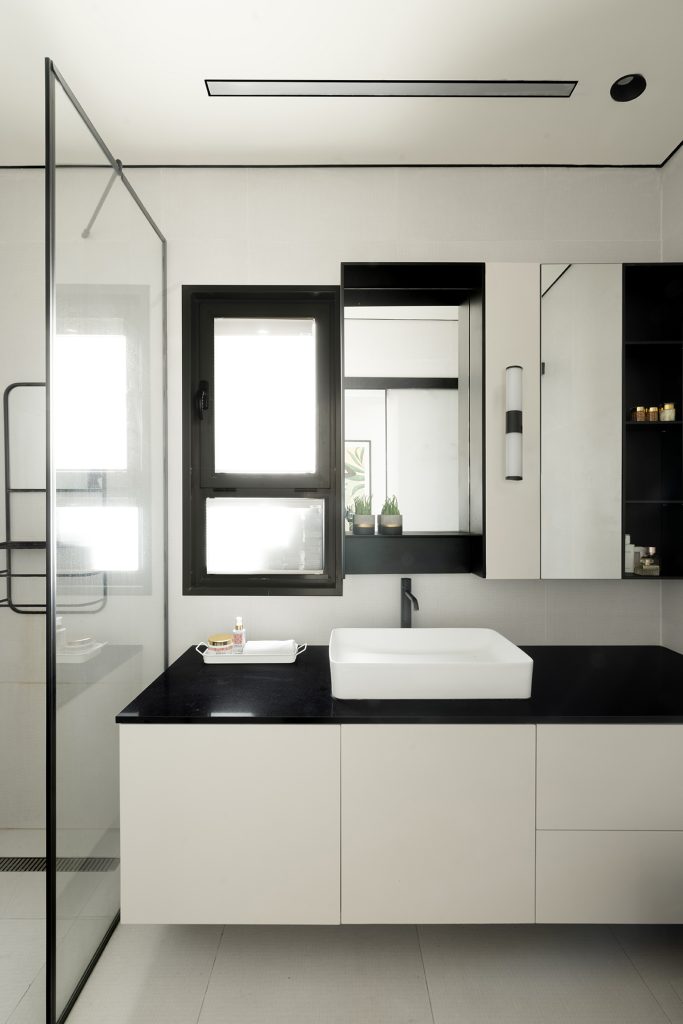 מקלחת מעוצבת לבנה עם מסגרת שחורה כיור לבן על משטח שחור